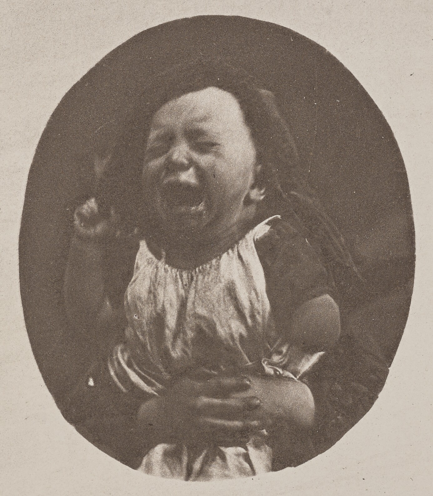 Enfant en pleurs maintenu par les bras d'un adulte Photographie ancienne d'un enfant en pleurs maintenu dans le cadre par les bras d'un adulte