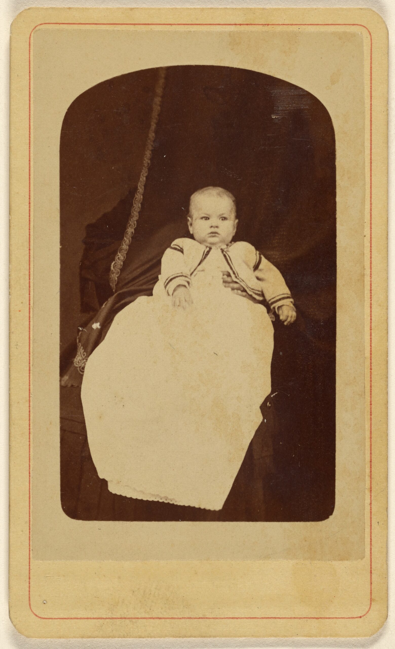 Bébé avec adulte dissimulé dans le fond sombre Portrait d'un bébé des années 1860 devant un adulte dissimulé dans le fond sombre
