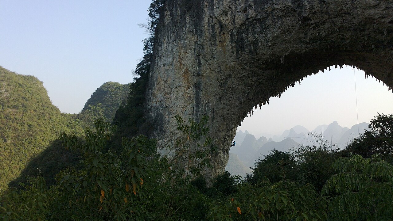Escalade sous l'arche de Moon Hill Grimpeur sous l'arche naturelle de Moon Hill à Yangshuo