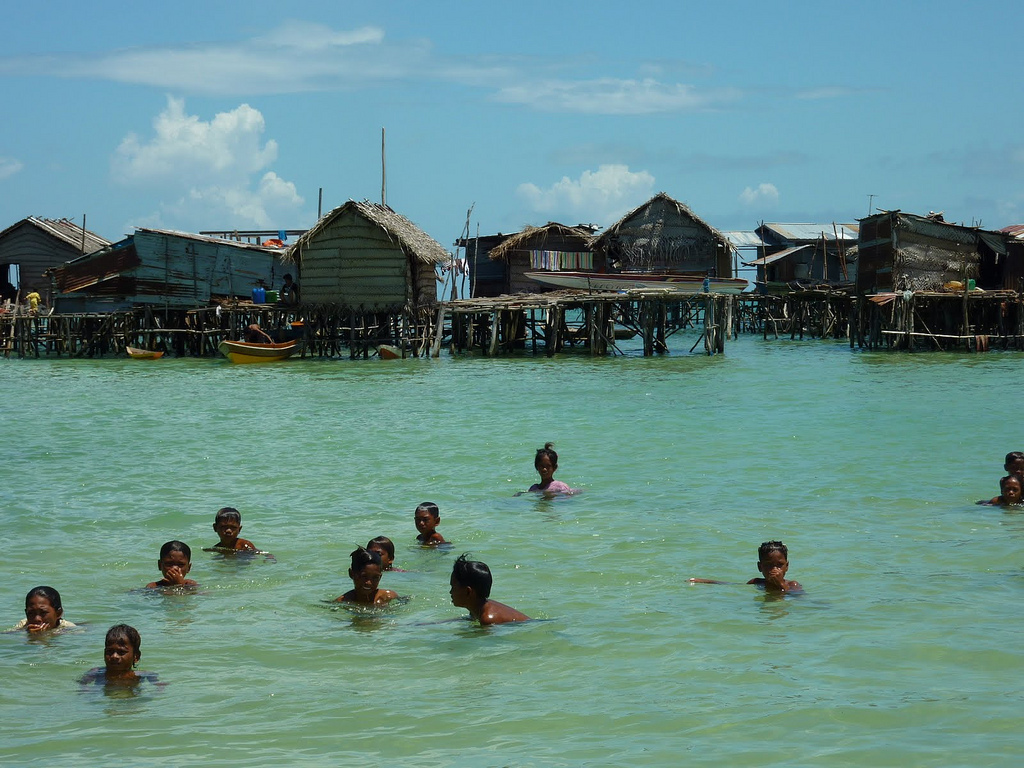Habitants Bajau Laut dans l’eau devant un village sur pilotis à Omadal Habitants Bajau Laut dans l’eau devant un village sur pilotis à Omadal
