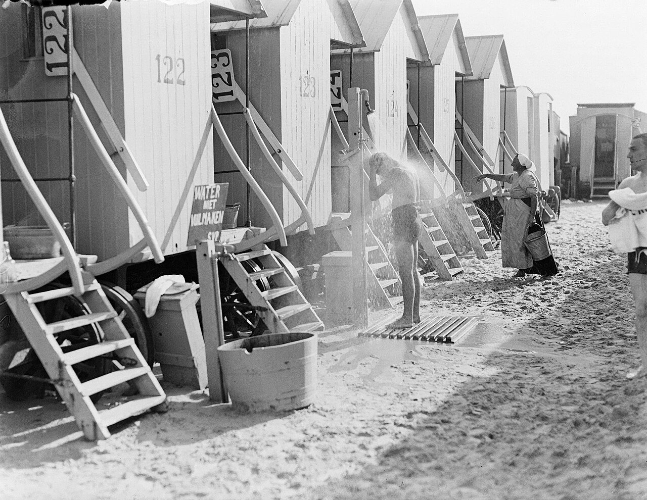 Garçon prenant une douche entre les cabines de bain de Scheveningen en 1932 Garçon prenant une douche entre les cabines de bain de Scheveningen en 1932