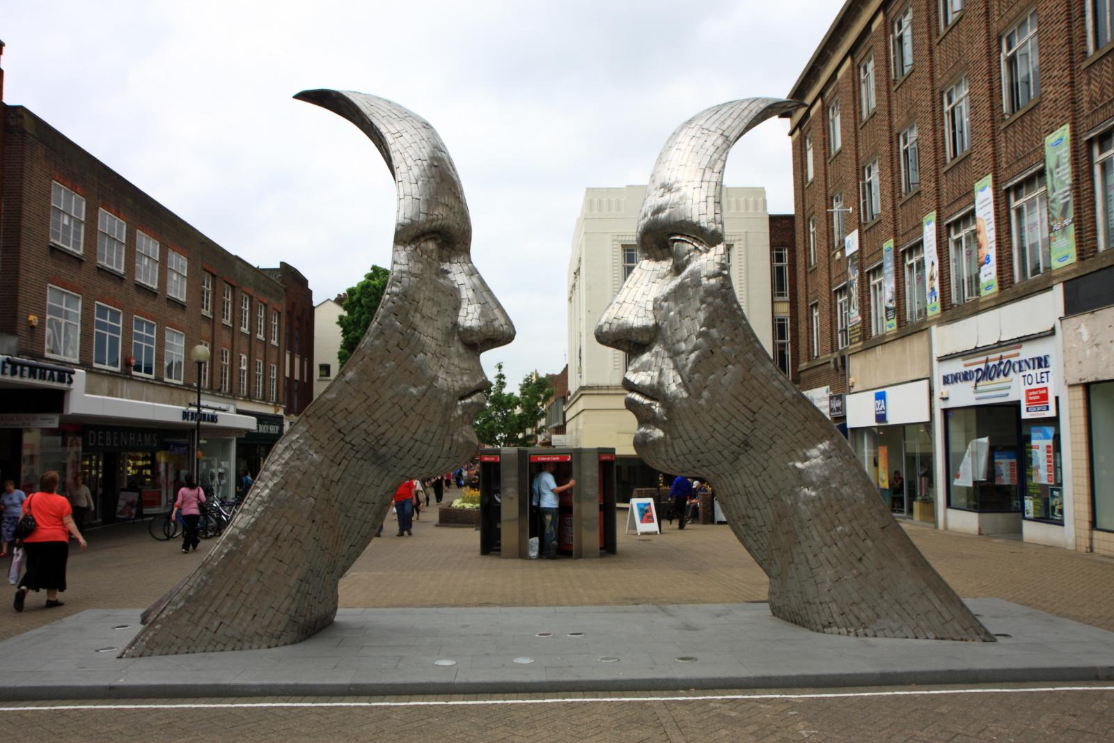 Les deux visages géants en acier de Reflections of Bedford par Rick Kirby Les deux visages géants en acier de Reflections of Bedford par Rick Kirby